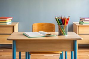 Empty classroom desk with books and pencils.
